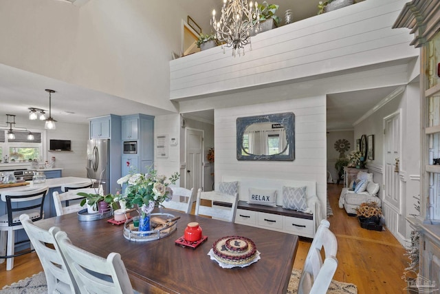 dining space with ornamental molding, an inviting chandelier, and light hardwood / wood-style floors