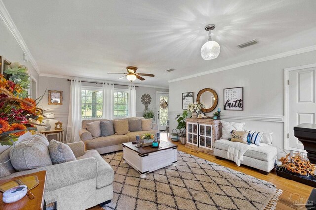 living room with ornamental molding, ceiling fan, and light wood-type flooring