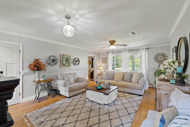 living room with crown molding, ceiling fan, and light wood-type flooring