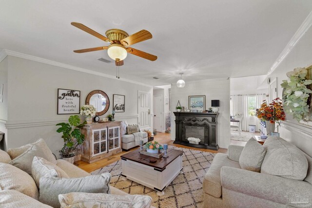 living room featuring crown molding, ceiling fan, and light hardwood / wood-style flooring