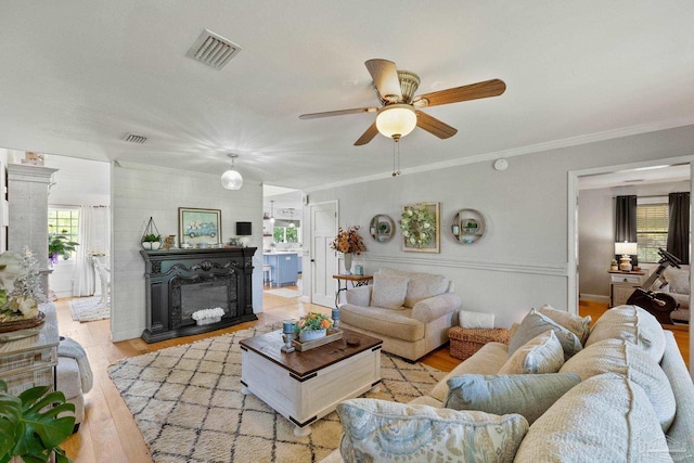 living room with crown molding, a wealth of natural light, and light hardwood / wood-style flooring