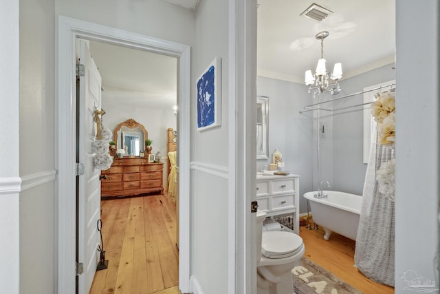 bathroom featuring toilet, crown molding, a notable chandelier, hardwood / wood-style flooring, and a washtub