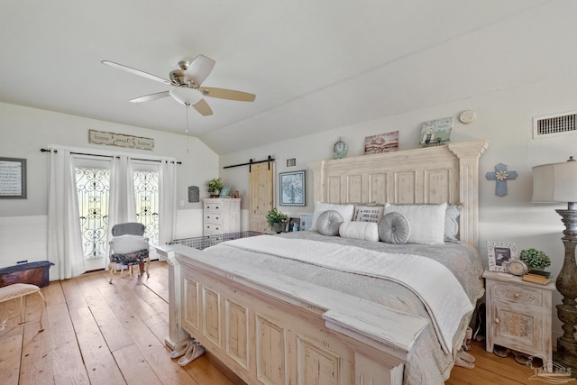 bedroom featuring ceiling fan, a barn door, vaulted ceiling, light hardwood / wood-style floors, and access to exterior