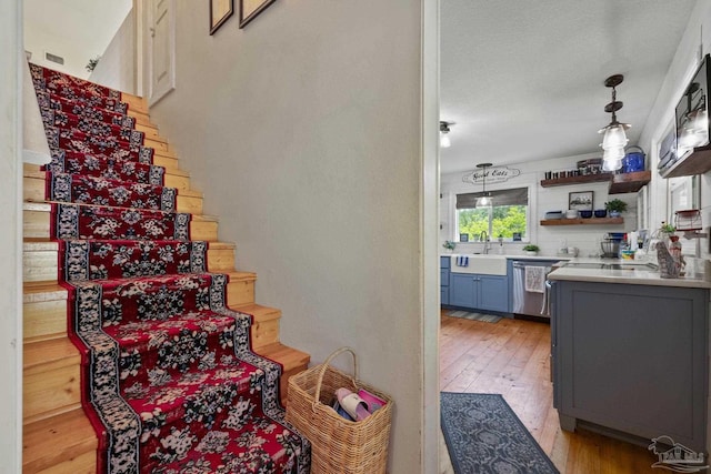 staircase with sink, a textured ceiling, and light wood-type flooring