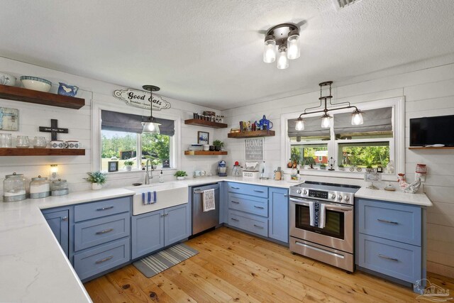 kitchen with pendant lighting, sink, appliances with stainless steel finishes, light hardwood / wood-style floors, and a textured ceiling