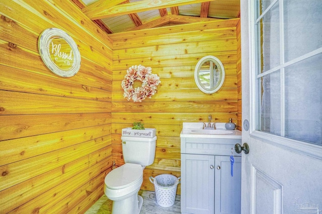 bathroom featuring wood walls, toilet, vanity, and vaulted ceiling