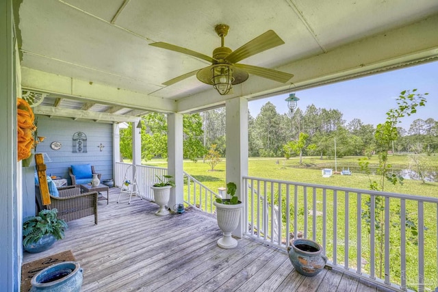 wooden terrace featuring ceiling fan and a lawn