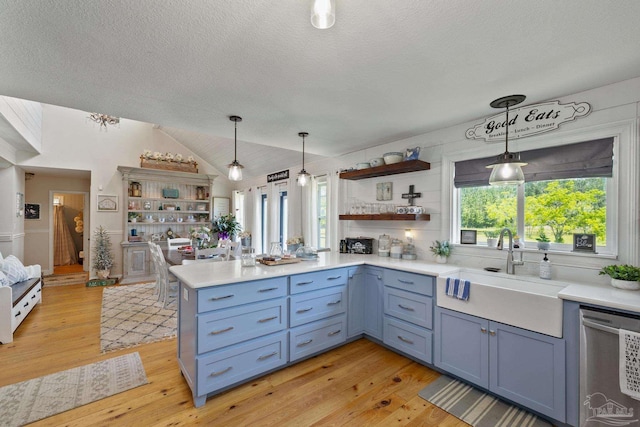 kitchen featuring hanging light fixtures, sink, stainless steel dishwasher, and kitchen peninsula