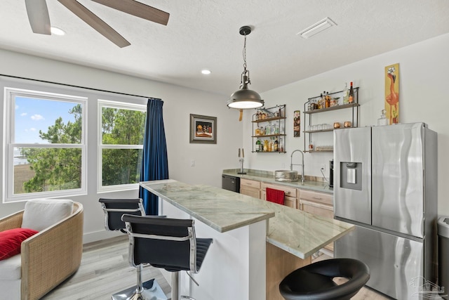2032 Bay Point Blvd, Milton, FL 32583 - kitchen featuring stainless steel fridge, a center island, a kitchen bar, light wood-type flooring, and light stone counters