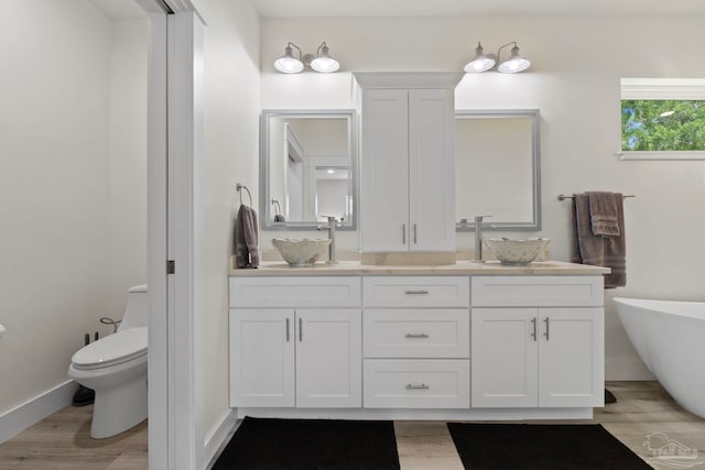 2032 Bay Point Blvd, Milton, FL 32583 - bathroom with double vanity, wood finished floors, and a freestanding tub