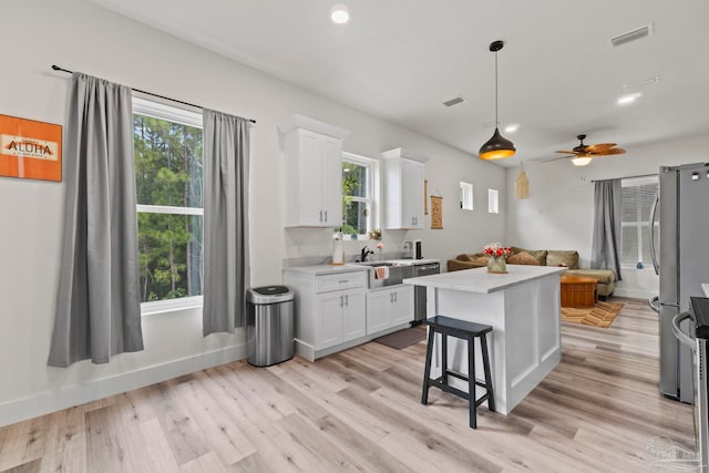 2032 Bay Point Blvd, Milton, FL 32583 - kitchen with light wood finished floors, light countertops, white cabinets, stainless steel appliances, and ceiling fan