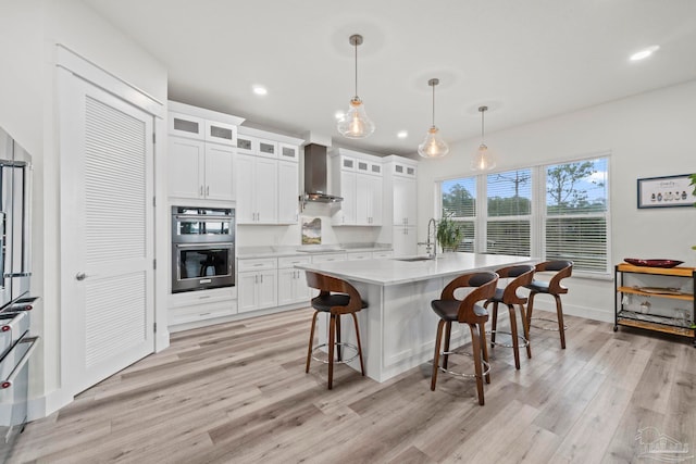 2032 Bay Point Blvd, Milton, FL 32583 - kitchen with wall chimney range hood, double oven, light wood finished floors, light countertops, and a kitchen breakfast bar