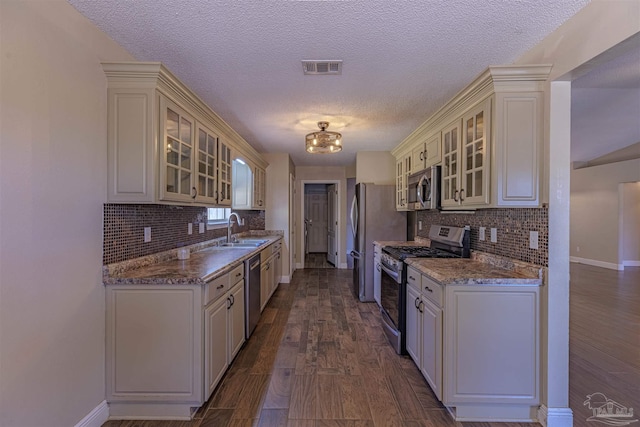 kitchen featuring light stone countertops, sink, a textured ceiling, and appliances with stainless steel finishes