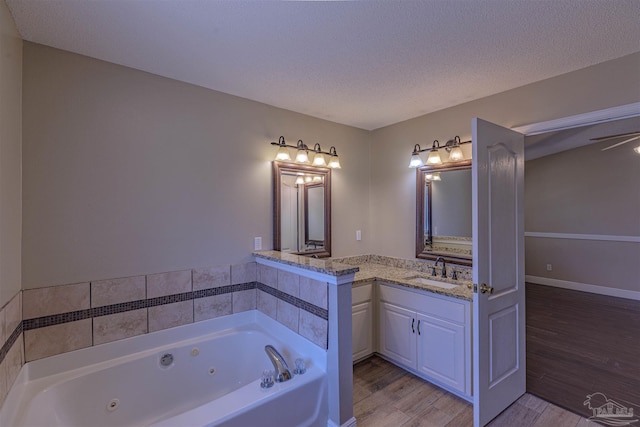 bathroom with vanity, wood-type flooring, a textured ceiling, and a bath