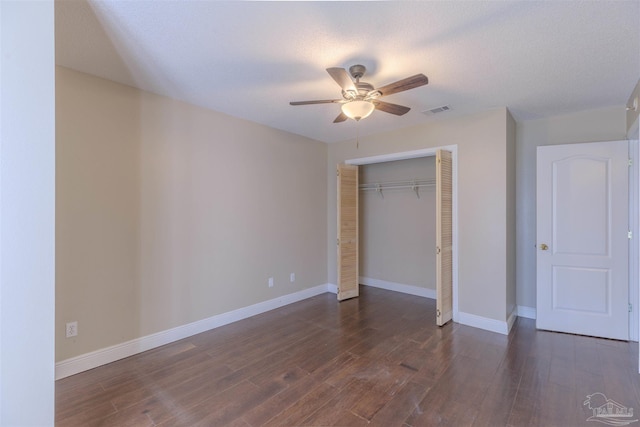 unfurnished bedroom featuring ceiling fan, a closet, dark wood-type flooring, and a textured ceiling