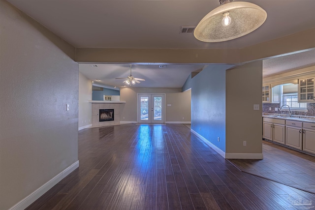 unfurnished living room with vaulted ceiling with beams, a healthy amount of sunlight, dark wood-type flooring, and french doors