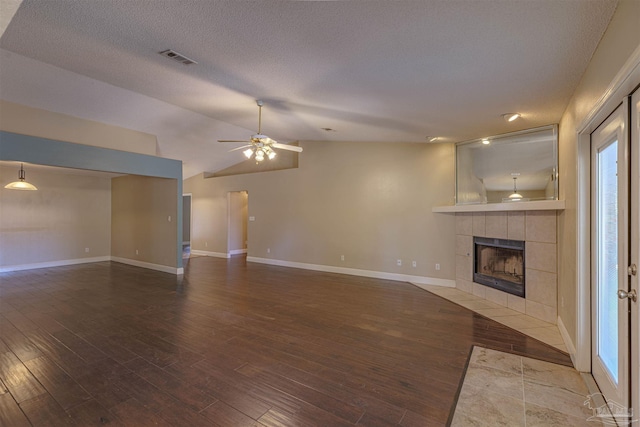 unfurnished living room with a fireplace, hardwood / wood-style flooring, vaulted ceiling, and ceiling fan