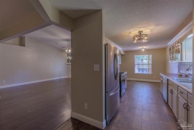 kitchen with white cabinets, appliances with stainless steel finishes, ceiling fan with notable chandelier, and sink