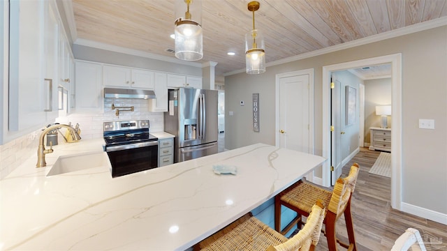 kitchen with light stone counters, pendant lighting, stainless steel appliances, hardwood / wood-style flooring, and sink