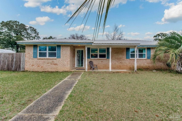 ranch-style house featuring a front yard, brick siding, metal roof, and fence