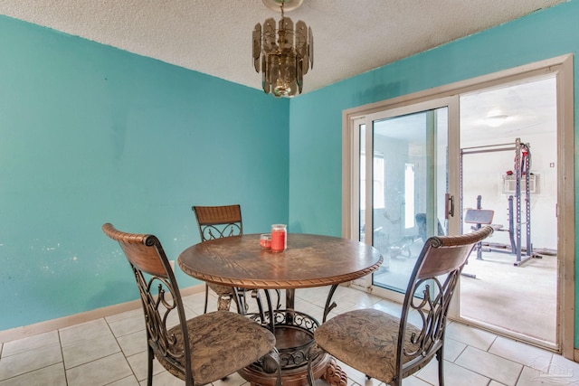 dining area with a textured ceiling, light tile patterned floors, baseboards, and a notable chandelier