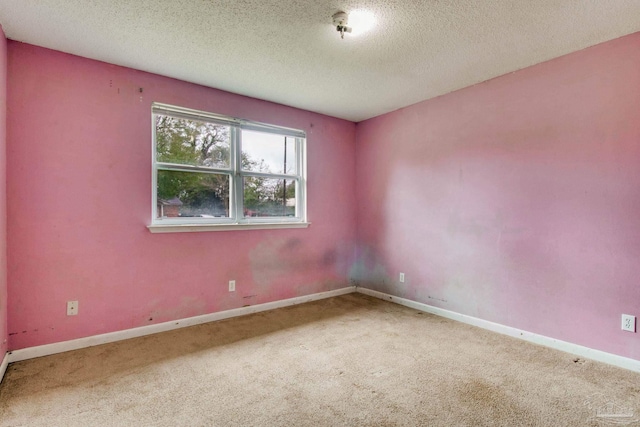 empty room featuring a textured ceiling, carpet, and baseboards