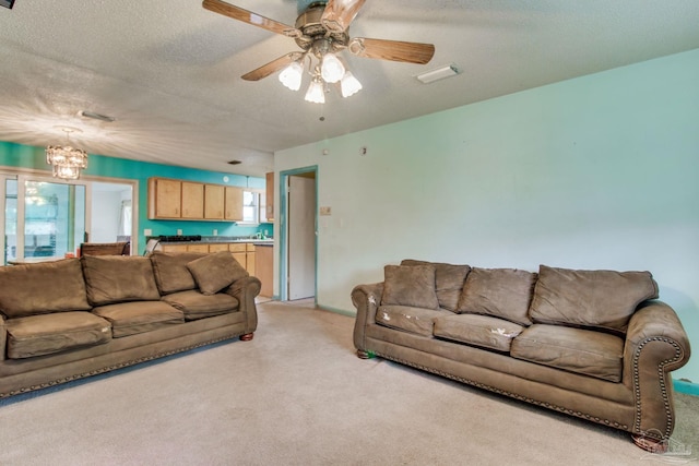 living room featuring light carpet, a textured ceiling, and ceiling fan with notable chandelier