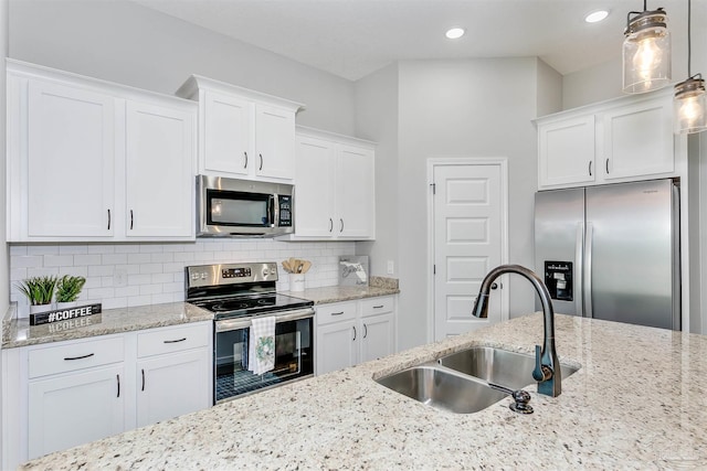 kitchen featuring appliances with stainless steel finishes, pendant lighting, white cabinets, and a sink