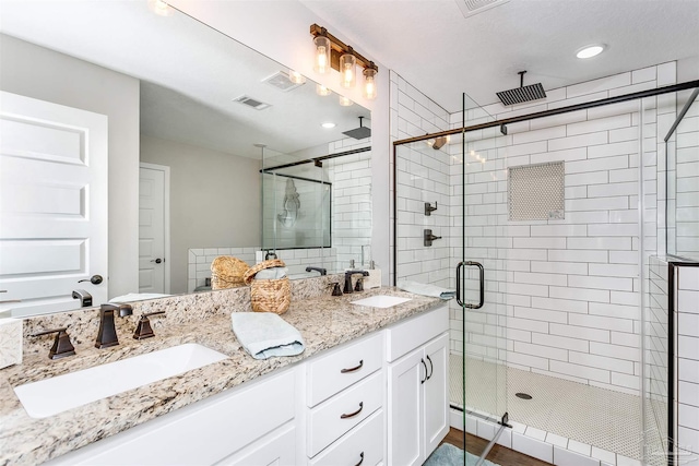 bathroom with double vanity, a stall shower, visible vents, and a sink