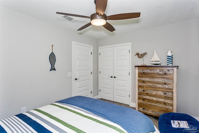 carpeted bedroom with a textured ceiling, a closet, visible vents, and a ceiling fan