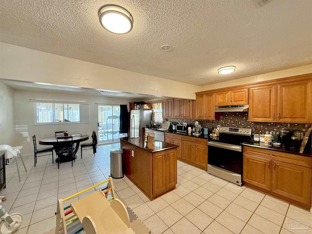 kitchen featuring a center island, backsplash, a textured ceiling, light tile patterned flooring, and stainless steel appliances