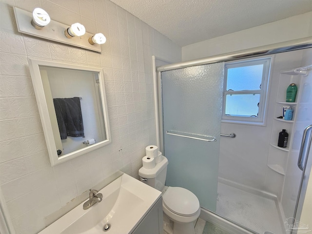 bathroom with vanity, toilet, a textured ceiling, tile walls, and an enclosed shower