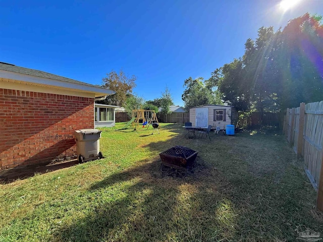 view of yard with a storage unit, a playground, and an outdoor fire pit