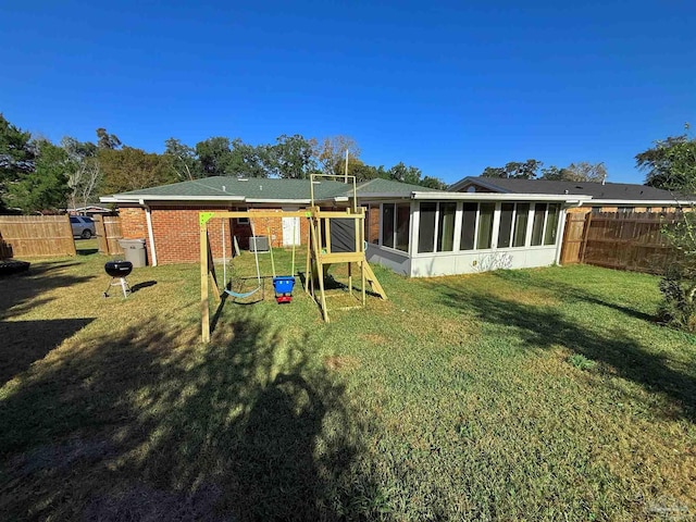 back of house with a playground, a sunroom, and a yard