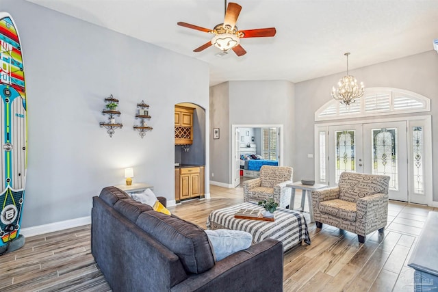 living room featuring french doors and ceiling fan with notable chandelier