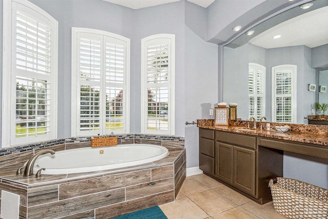 bathroom featuring vanity, a relaxing tiled tub, and tile patterned floors