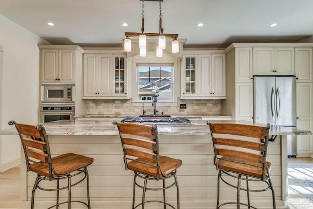 kitchen featuring decorative backsplash, light stone countertops, a kitchen island, and stainless steel appliances