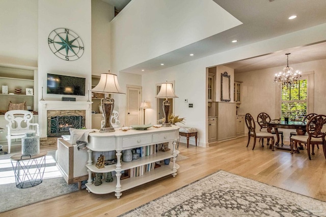 living room with an inviting chandelier, a high ceiling, and light hardwood / wood-style flooring