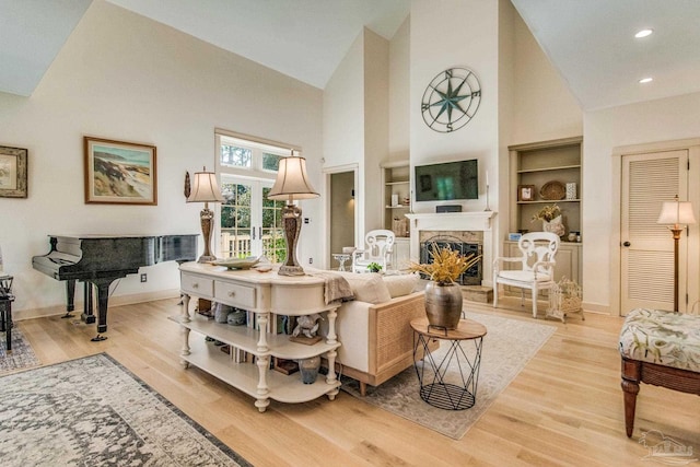 living room featuring built in shelves, french doors, high vaulted ceiling, and light hardwood / wood-style floors