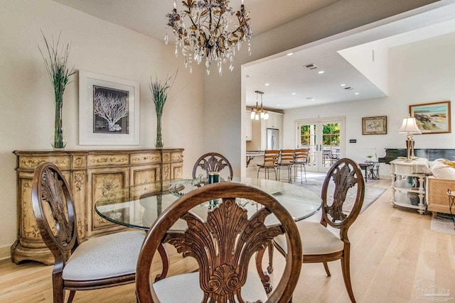 dining area with french doors, light hardwood / wood-style flooring, and a notable chandelier