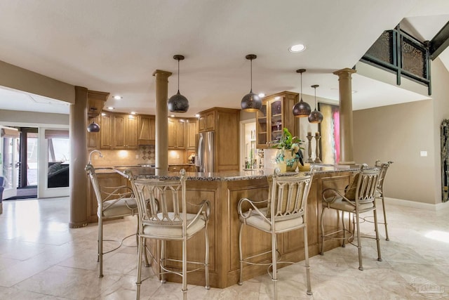 4552 Bayside Dr, Milton, FL 32583 - kitchen featuring dark stone countertops, brown cabinetry, a peninsula, decorative backsplash, and stainless steel fridge
