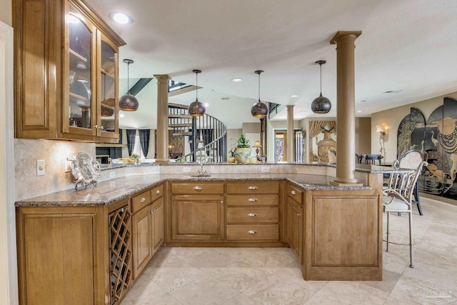 4552 Bayside Dr, Milton, FL 32583 - kitchen with brown cabinets, stone countertops, a breakfast bar, and decorative columns