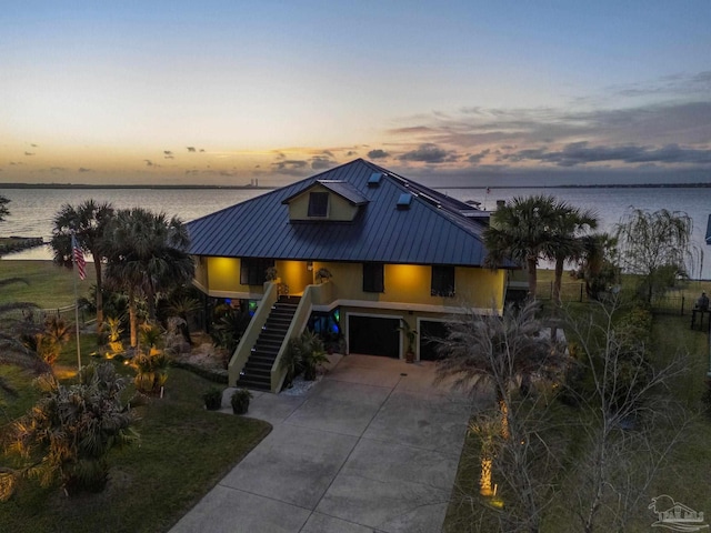 4552 Bayside Dr, Milton, FL 32583 - coastal home featuring a standing seam roof, an attached garage, stairs, concrete driveway, and metal roof