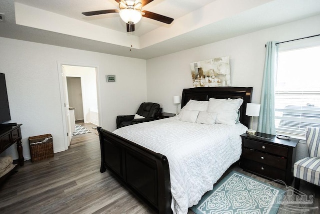 bedroom featuring ceiling fan, wood-type flooring, and a tray ceiling