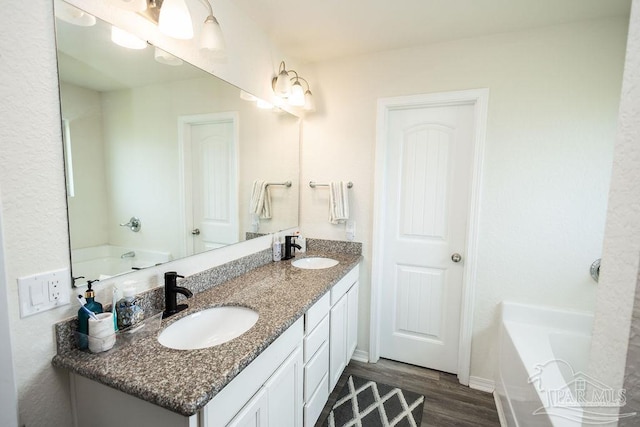 bathroom featuring double sink vanity, a tub to relax in, and wood-type flooring