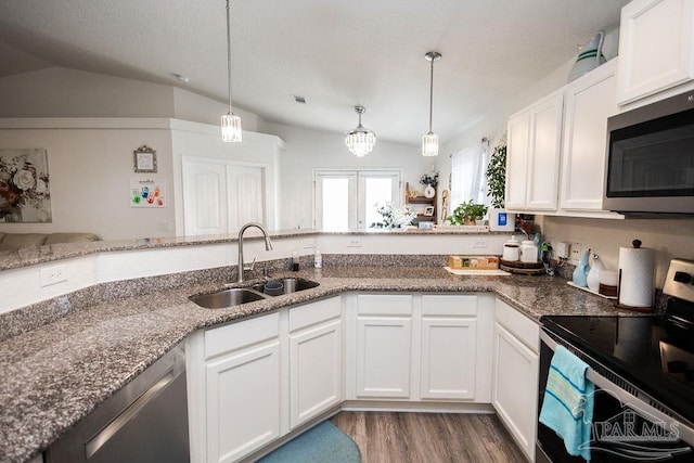 kitchen with dark stone countertops, stainless steel appliances, light wood-type flooring, sink, and kitchen peninsula