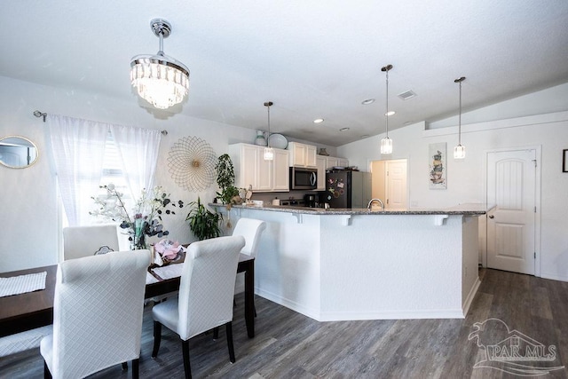 dining space featuring dark wood-type flooring, vaulted ceiling, and an inviting chandelier