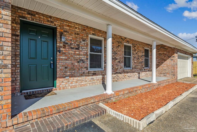 720 Lambert St, Pensacola, FL 32505 - view of exterior entry featuring brick siding, a porch, and an attached garage