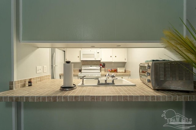 kitchen with white cabinets, white appliances, kitchen peninsula, and sink