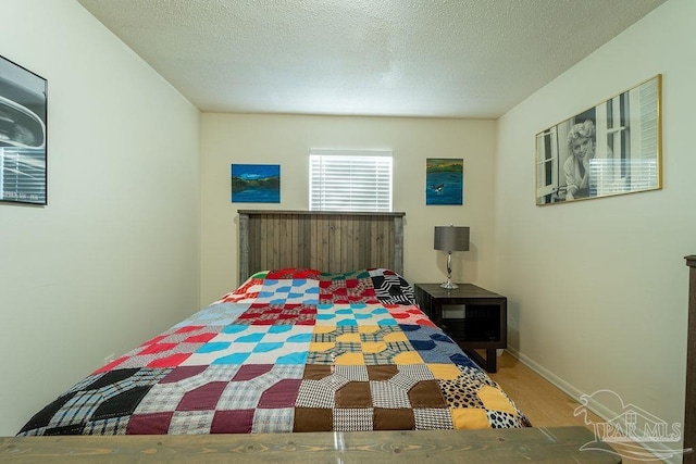 bedroom with a textured ceiling and hardwood / wood-style flooring